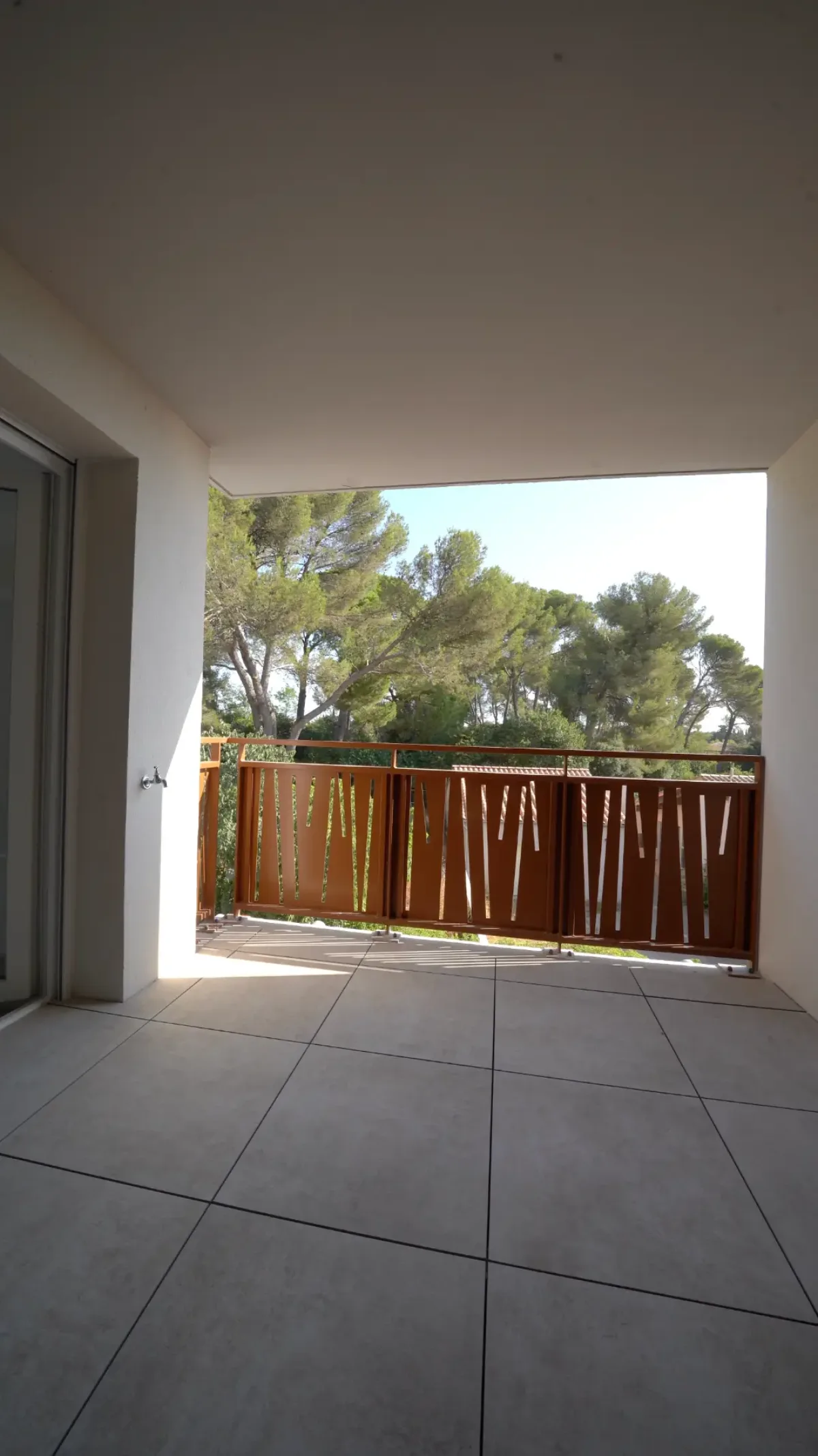 Terrasse du T3 A202, carrelée et couverte, ouverte sur les pins